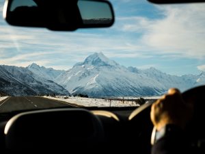 man driving towards mountains